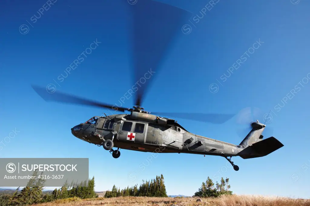 A Sikorsky UH-60 Blackhawk helicopter, configured for medevac operations, lifts of from a landing zone at 10,000 feet above sea level, in Colorado's Rocky Mountains. This aircraft is a U.S. Army UH-60 Dustoff Air Ambulance Medevac Blackhawk.