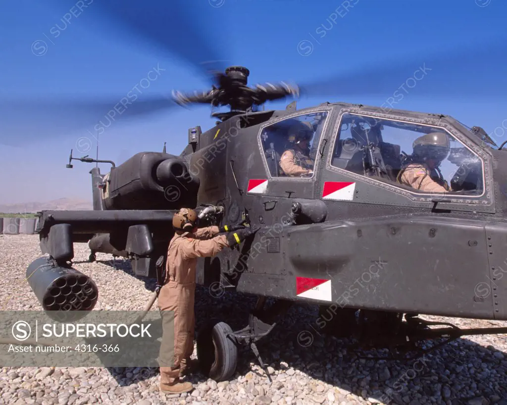 An Army Ground Crewman Refuels an AH-64 Apache Gunship