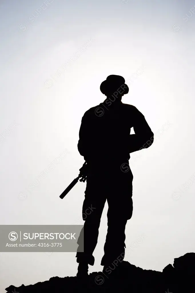 Silhouette of a U.S. Marine Holding a Rifle with a Suppressor, at a Small, Remote, Austere U.S. Marine Corps Combat Outpost in Afghanistan's Helmand Province