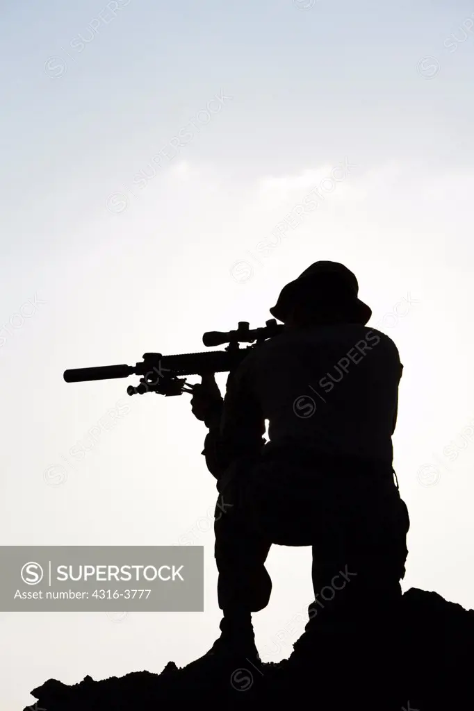 Silhouette of a U.S. Marine Aiming a Rifle with a Suppressor, at a Small, Remote, Austere U.S. Marine Corps Combat Outpost in Afghanistan's Helmand Province