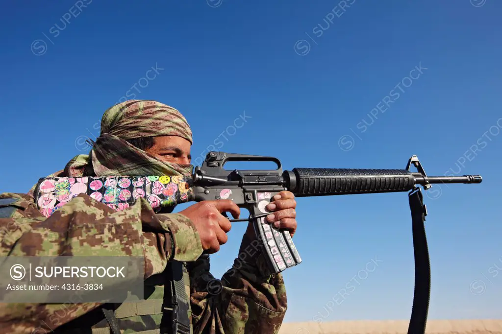 An Afghan National Army Soldier Aims a U.S. Supplied M16 That He Has Adorned With Children's Colorful Stickers