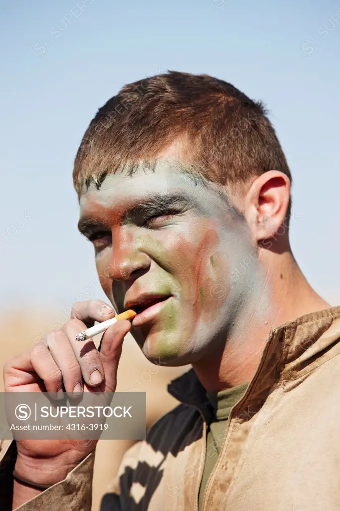 A U.S. Marine, Wearing Face paint, Smokes a Cigarette Before a Combat Operation in Afghanistan's Helmand Province