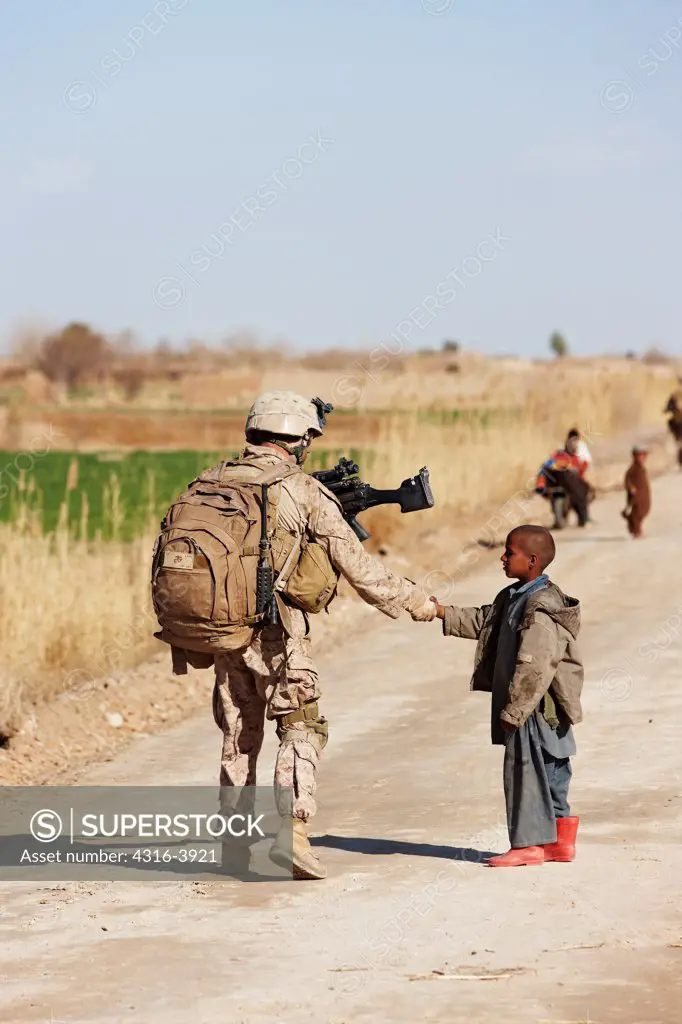 A U.S. Marine on Patrol in Afghanistan's Helmand Province Shakes Hands with a Local Boy