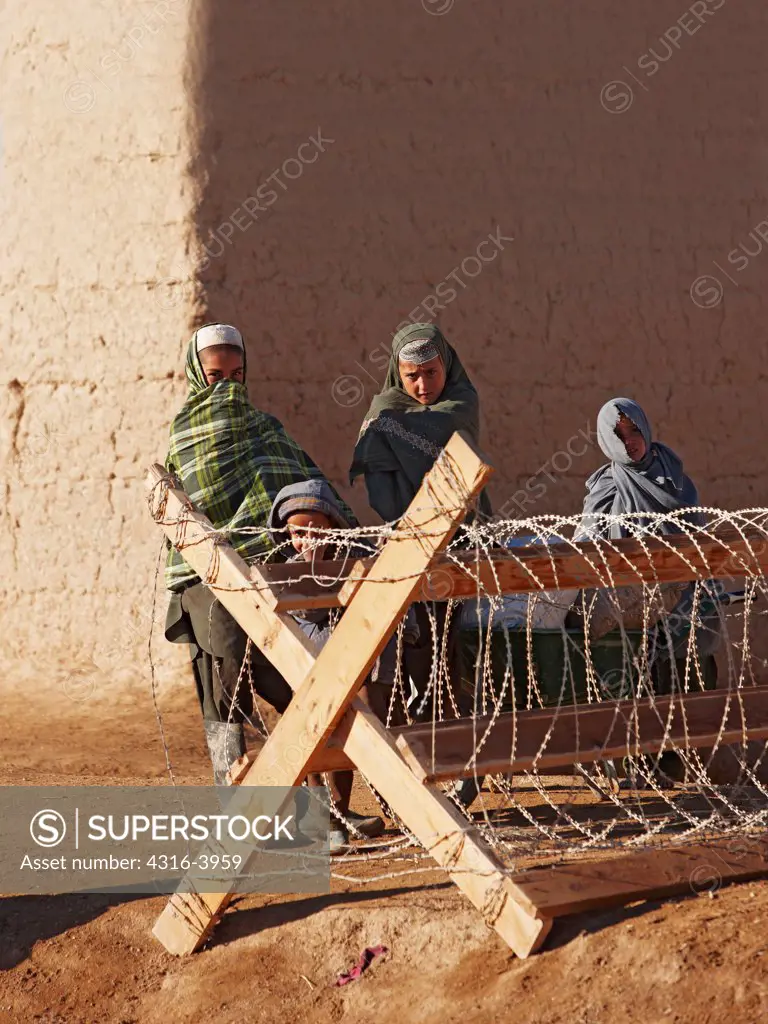 Young Children, One Flipping Off The Photographer, Stand Behind a Line of Concertina Razor Wire Outside of a U.S. Marine Corps Forward Operating Base in the Town of Marjah, Helmand Province, Afghanistan