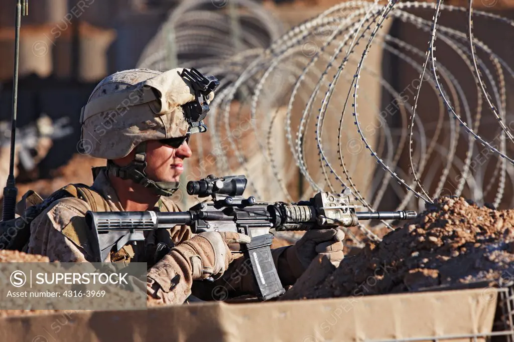 A U.S. Marine Looks Through a Coil of Concertina Razor Wire at a Small Combat Outpost in Afghanistan's Helmand Province