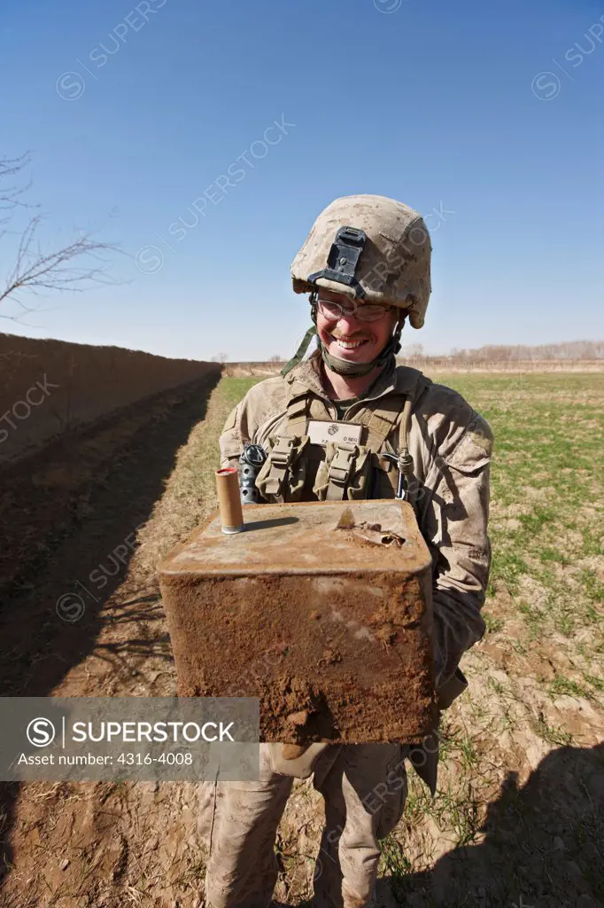 U.S. Marine Holds a Box of Weapons He Just Discovered and Unearthed From a Hidden Weapons Cache in Afghanistan's Helmand Province