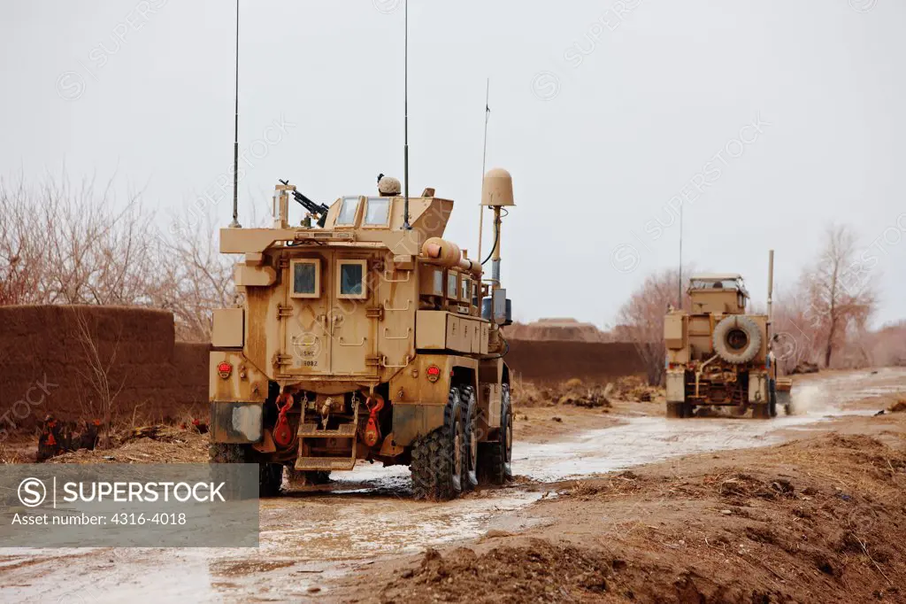 Convoy of U.S. Marine Corps MRAPs, or Mine Resistant Ambush Protected Vehicles, Drive Through Muddy Road, Helmand Province of Afghanistan