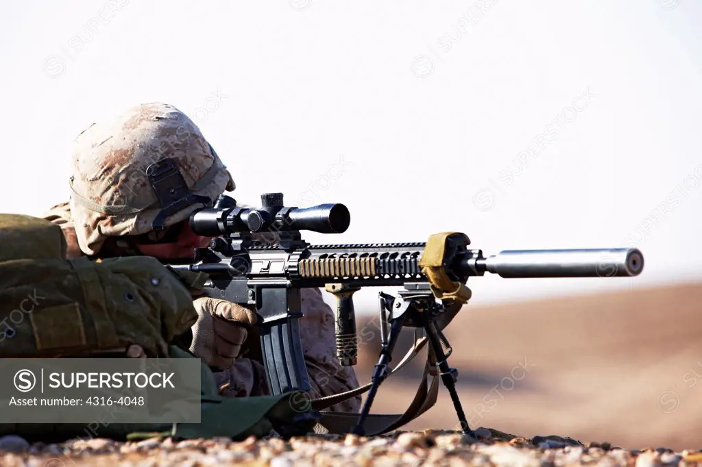 A U.S. Marine Designated Marksman Peers Through the Scope of a High Power Rifle With a Suppressor Mounted During a Combat Operation in Afghanistan's Helmand Province