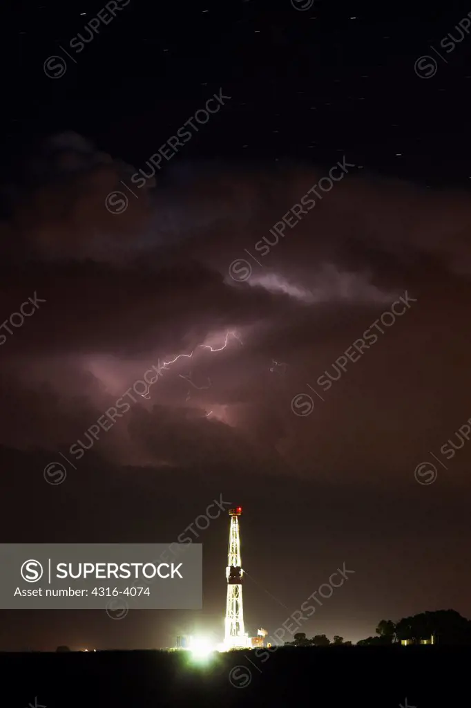 Night View of Natural Gas Drilling Rig with Lightning Storm Above