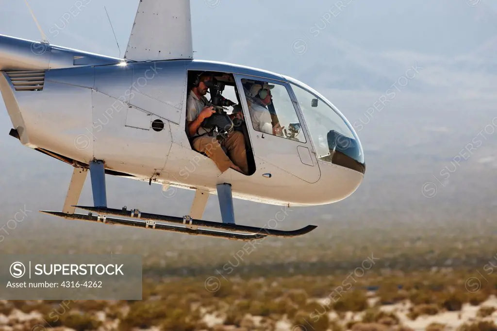 Helicopter Carrying Camera Operator in Desert Valley