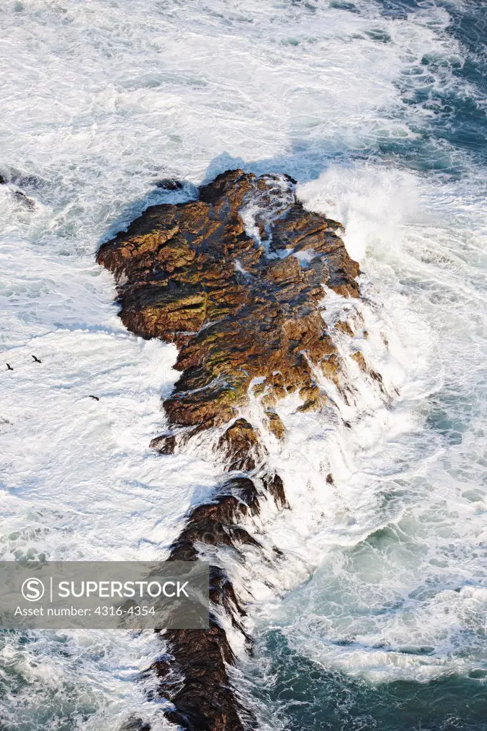Aerial View of Waves Breaking on Rocks
