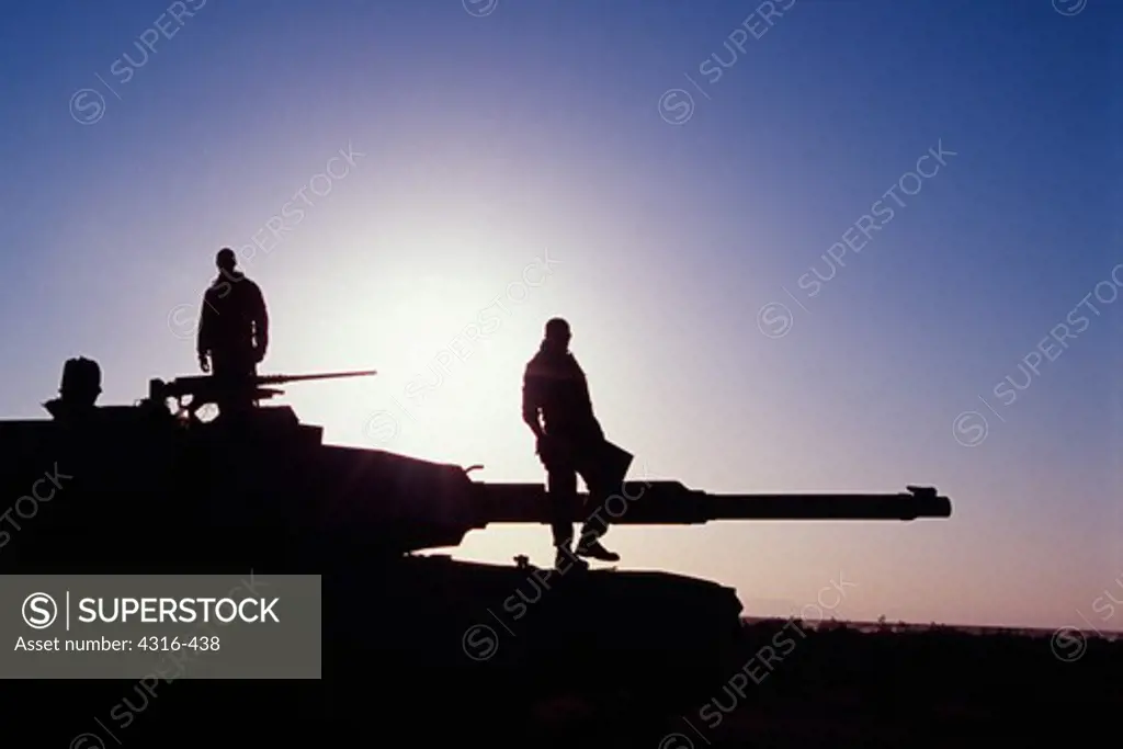 Silhouettes of US Marines on M1A1 Battle Tank at Sunrise