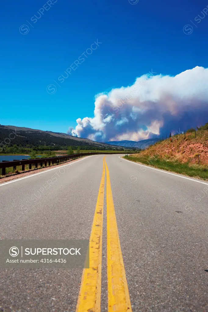 Road striking toward raging mountain wildfire, Colorado, USA