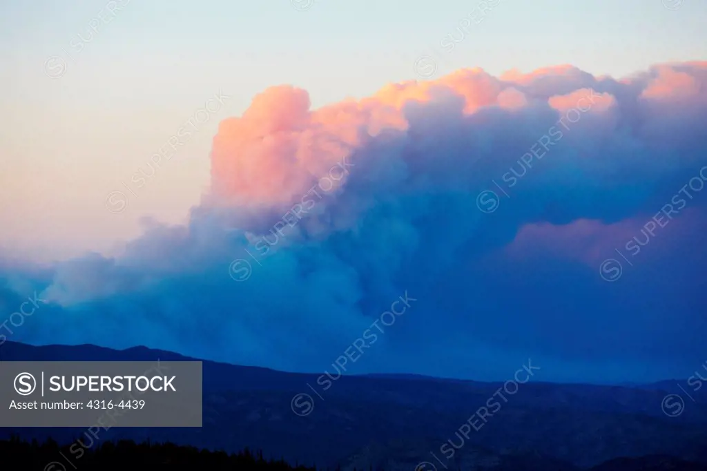 Sunset light on plume of smoke from raging mountain wildfire, as seen from 11,000 feet in Colorado's Rocky Mountains, USA