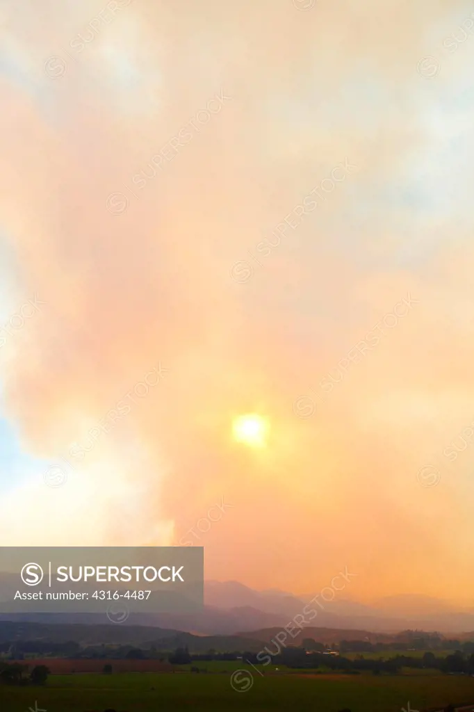 Rising plume of smoke from raging wildfire obscures setting sun, Colorado, USA