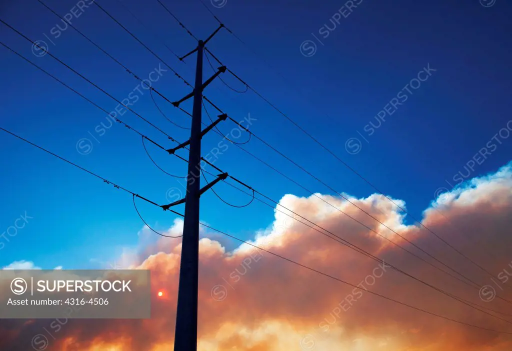 High voltage powerline, power pole, plume of smoke from raging mountain wildfire, Colorado, USA