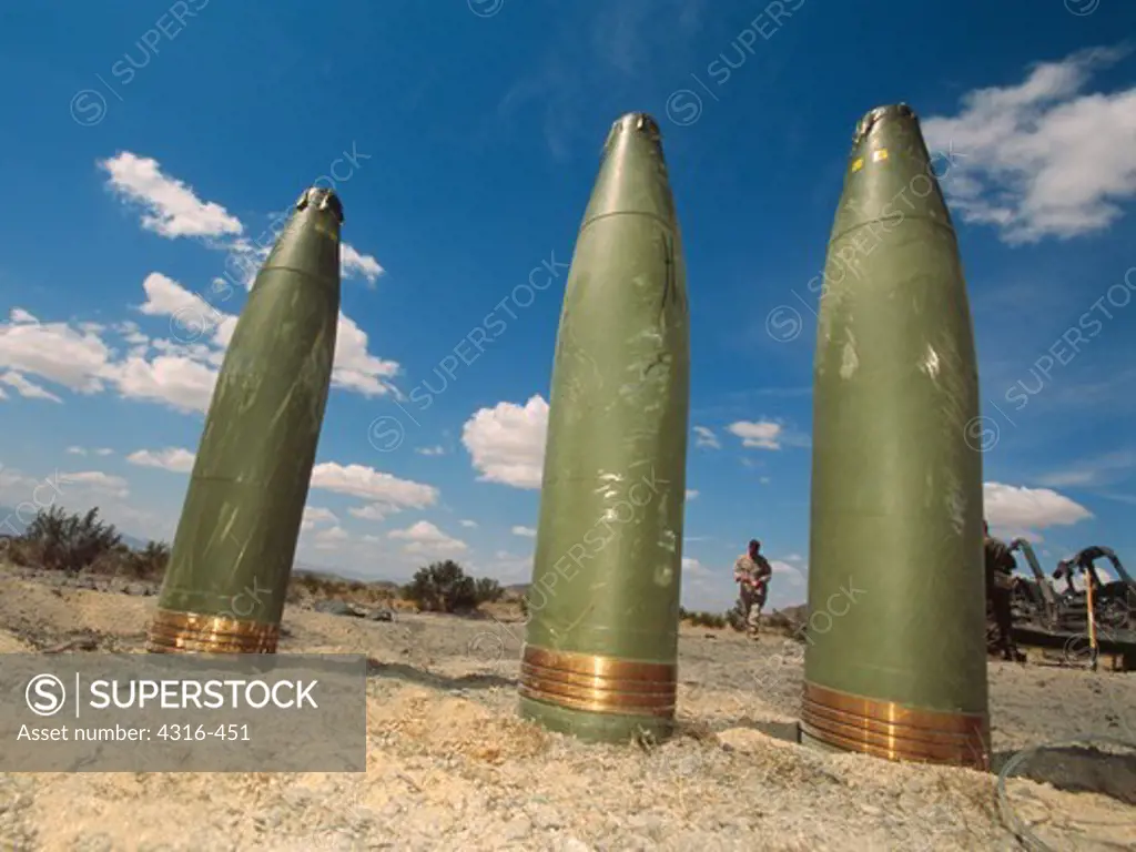 Three 155mm High Explosive Artillery Rounds Standing on End in the Desert