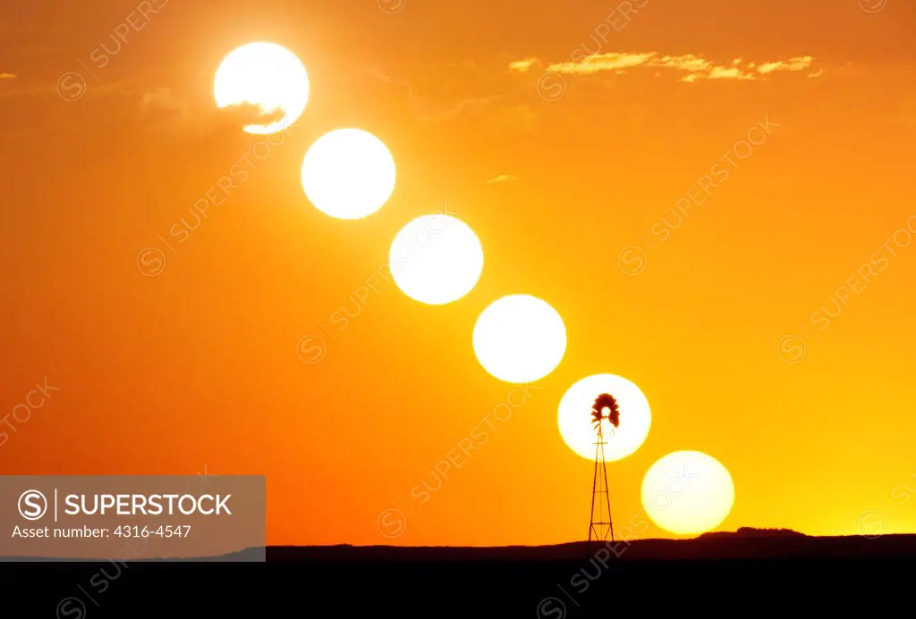 Sequence of the sun setting, silhouetting a lone windmill on plains, Colorado, USA