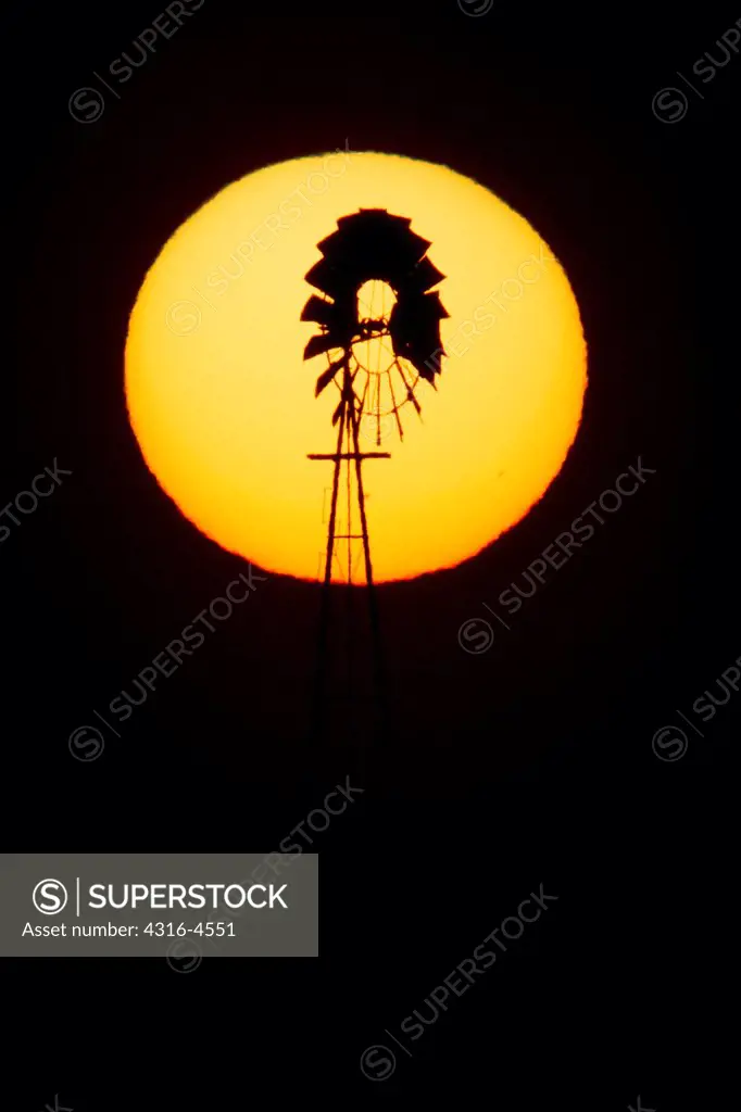 Setting sun silhouettes windmill on eastern plains of Colorado, USA