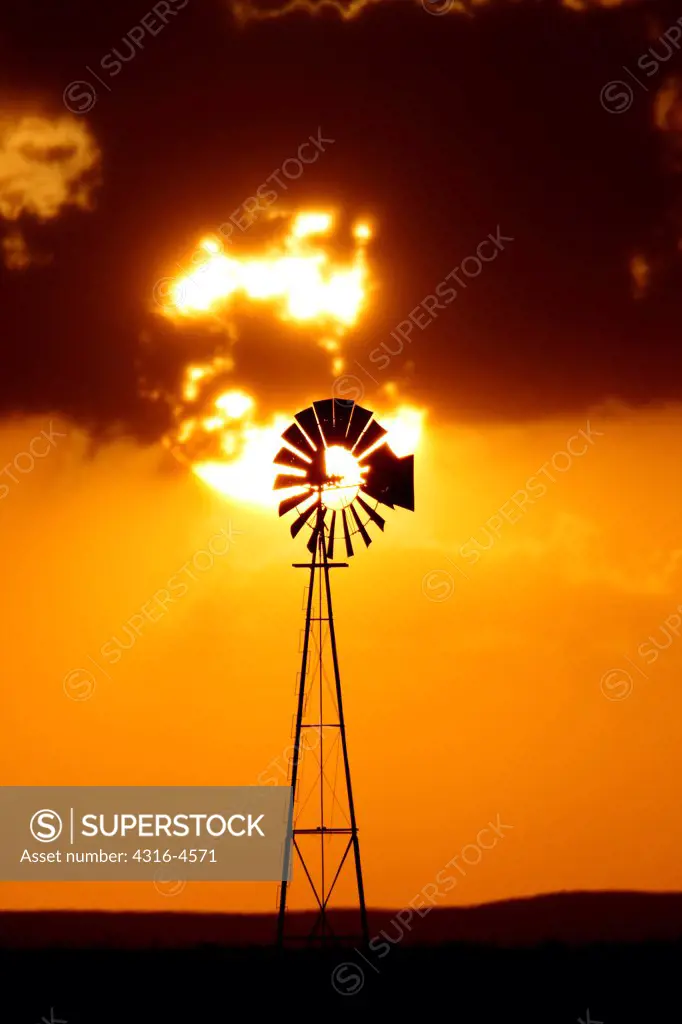 Telephoto view of setting sun and lone windmill