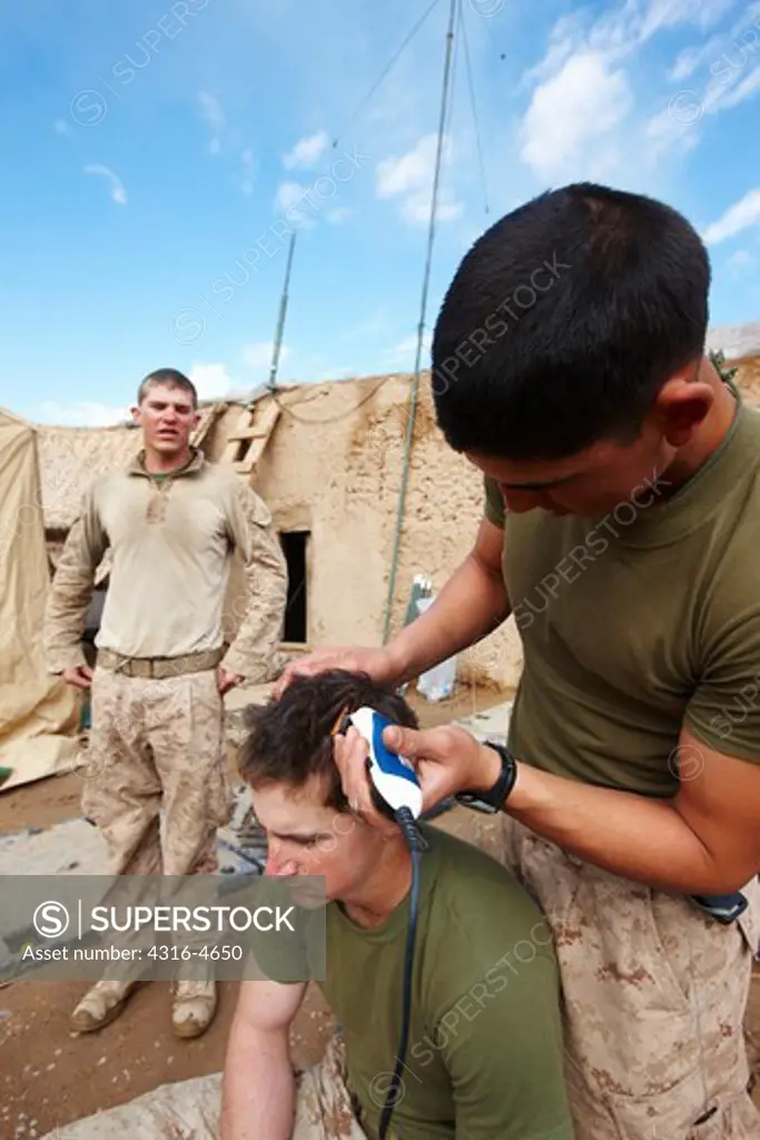 United States Marine cuts the hair of another Marine at a small, remote, austere combat outpost in Afghanistan's Helmand Province