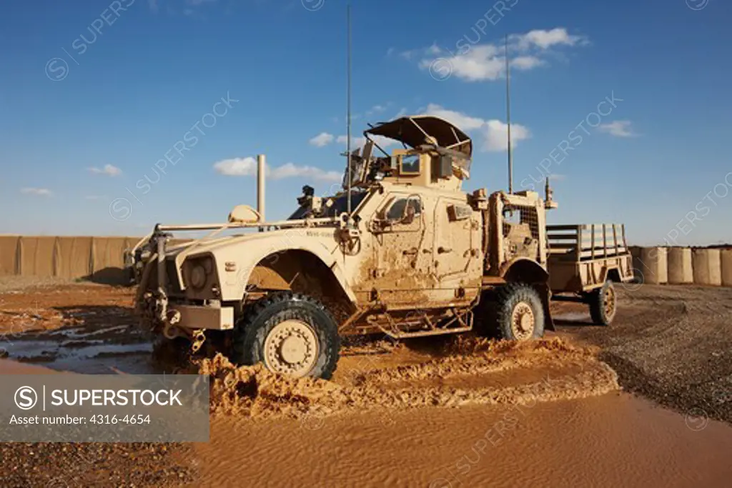 M-ATV, or Mine Resistant, Ambush Protected, All Terrain Vehicle drives through puddles on a muddy dirt road in Afghanistan's Helmand Province