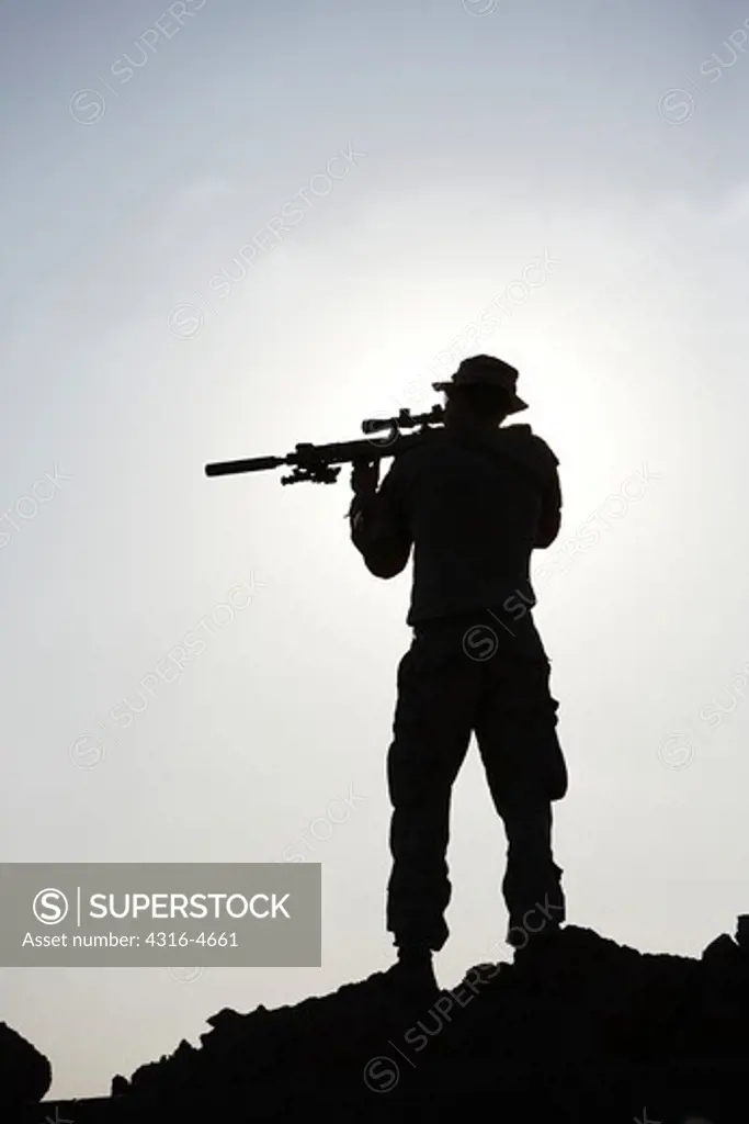 Silhouette of a United States Marine aiming a rifle during a combat operation in Afghanistan's Helmand Province