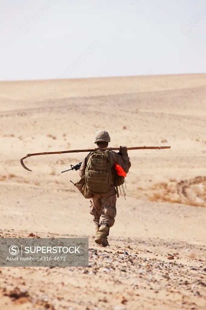 United States Marine during combat operation in Afghanistan's Helmand Province carries a pole used to check for improvised explosive devices