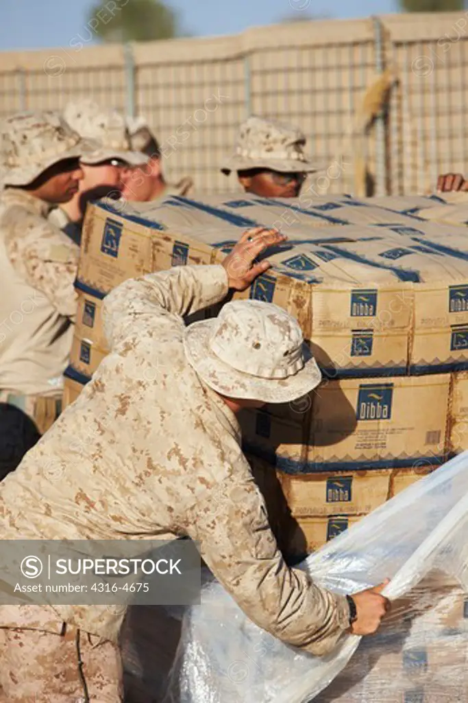 United States Marines unload boxes of bottled water at a remote, austere forward operating base in Afghanistan's Helmand Province