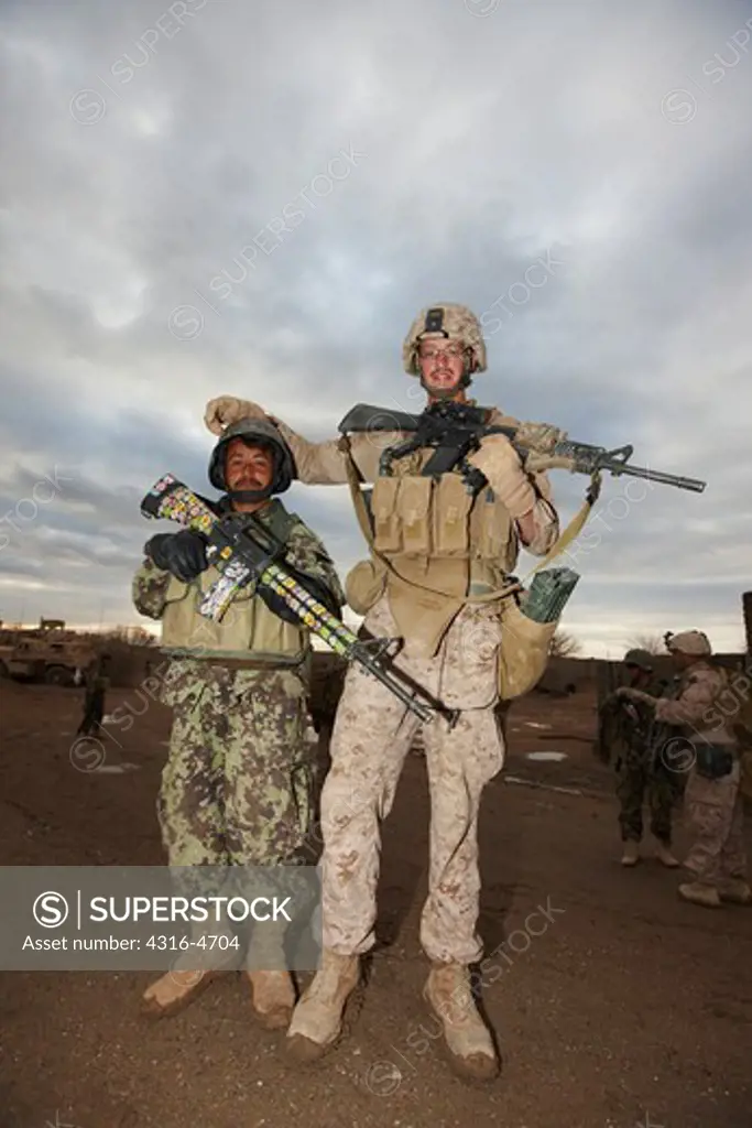 United States Marine poses with an Afghan National Army soldier who holds an M-16 adorned with childish stickers, Helmand Province of Afghanistan