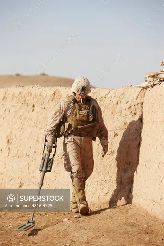 United States Marine combat engineer uses a metal detector to sweep for hidden explosives and weapons caches during a combat operation in Afghanistan's Helmand Province