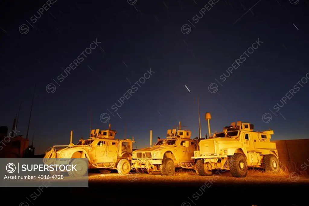 Night view of three MRAPs, or mine resistant, ambush protected vehicles, emphasis on stars and meteorite