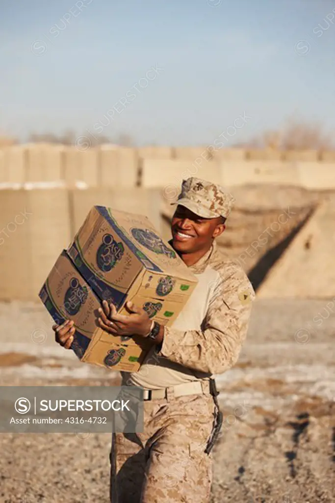United States Marine carries boxes of bottled water at a forward operating base in Afghanistan's Helmand Province