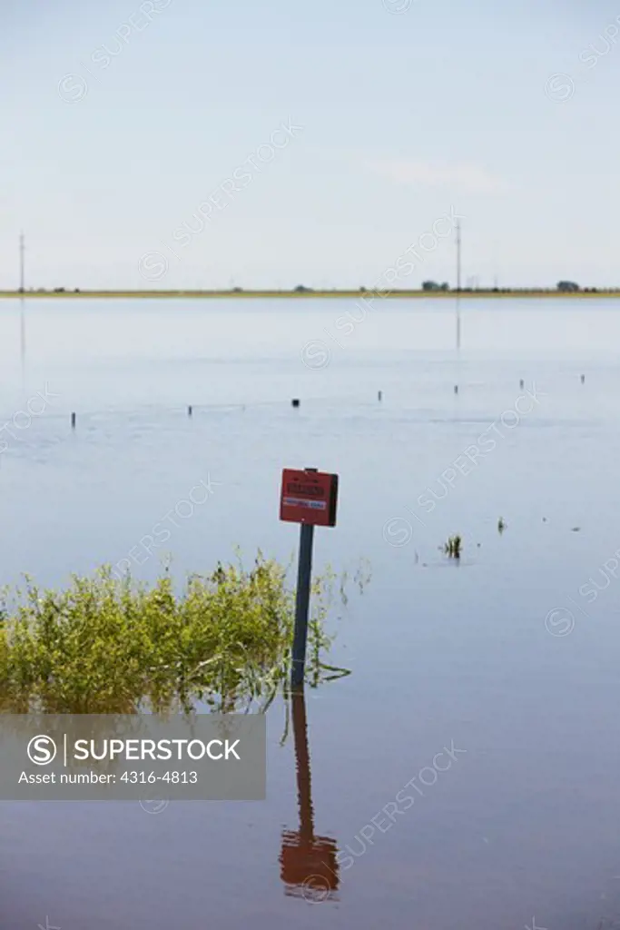 Flooded field with sign indicating buried fiber optic cable, Oklahoma