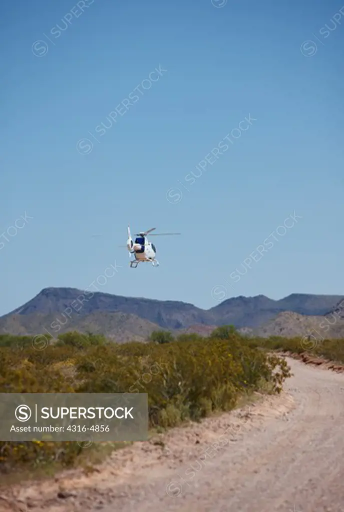 Border patrol helicopter flying low over the United States - Mexico border in southern Arizona