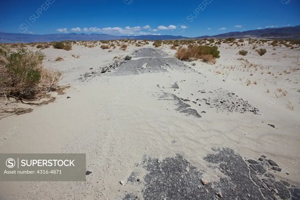 Sand dunes overtaking old paved road, Olancha Dunes, near Olancha, California