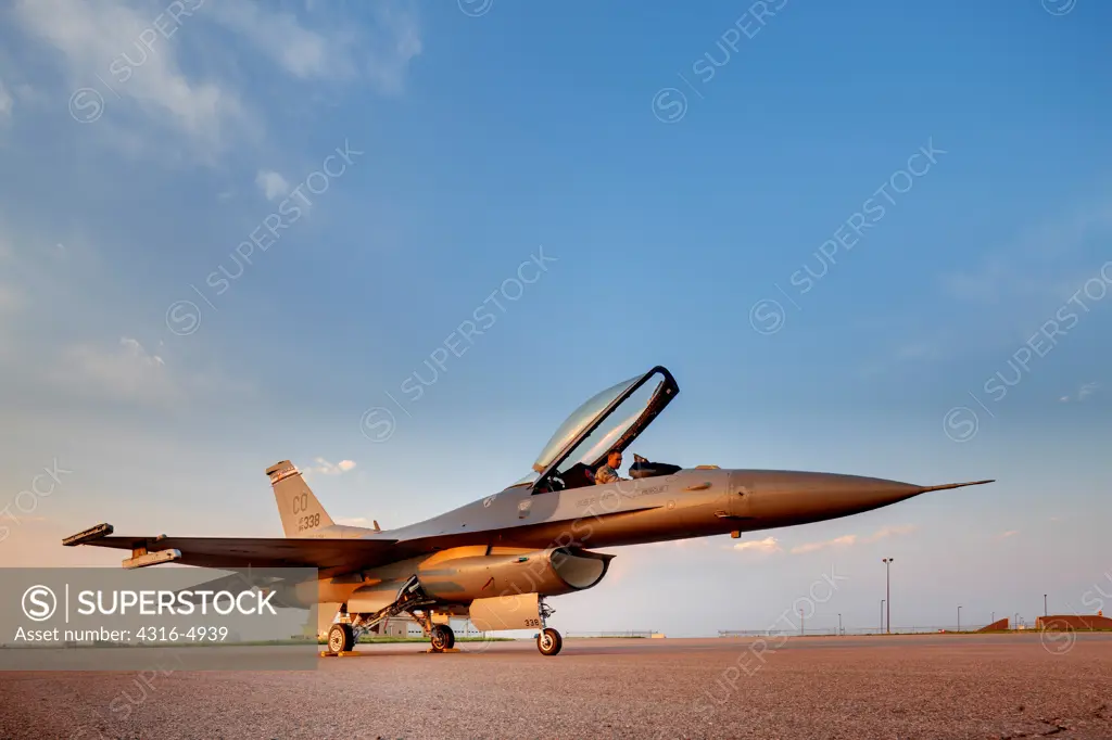 Pilot in cockpit of F-16 Fighting Falcon at dusk
