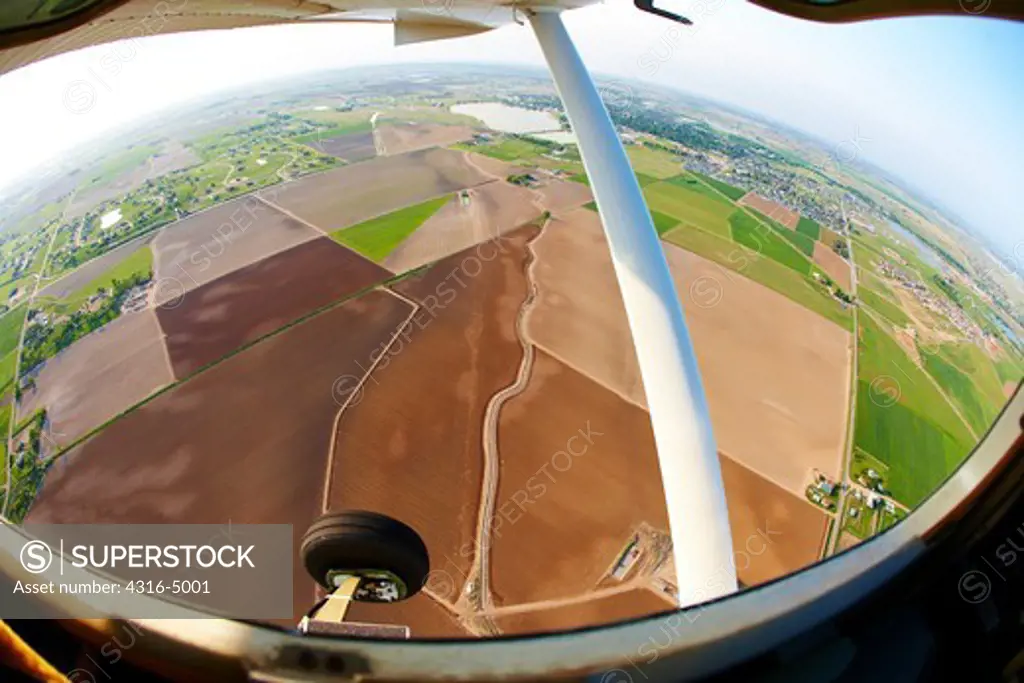 Fisheye view of aircraft landing gear and agriculture fields below, Colorado