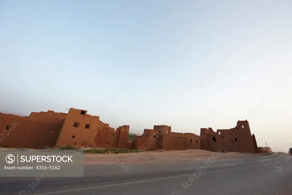 Ruins of earthen dwellings, modern paved road, Morocco