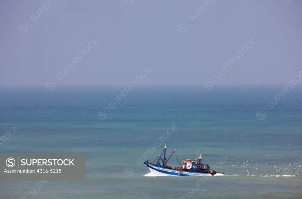 Fishing boat embarks into the Atlantic Ocean from the port at Tarfaya, in southern Morocco