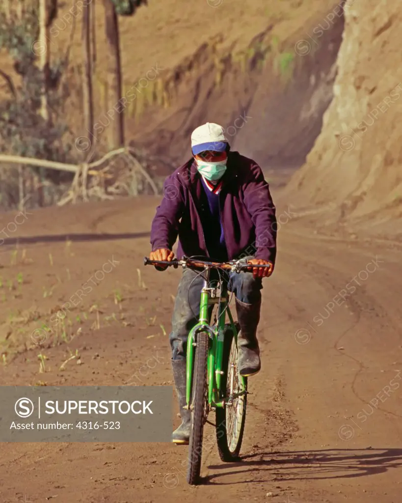 A Bicyclist Wears a Mask to Protect his Lungs From Volcanic Dust