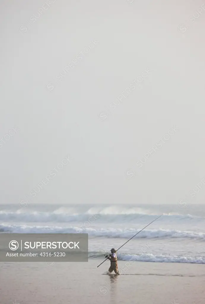 Fisherman, with large fishing pole, fishing on Atlantic coast of Morocco, near the town of Agadir