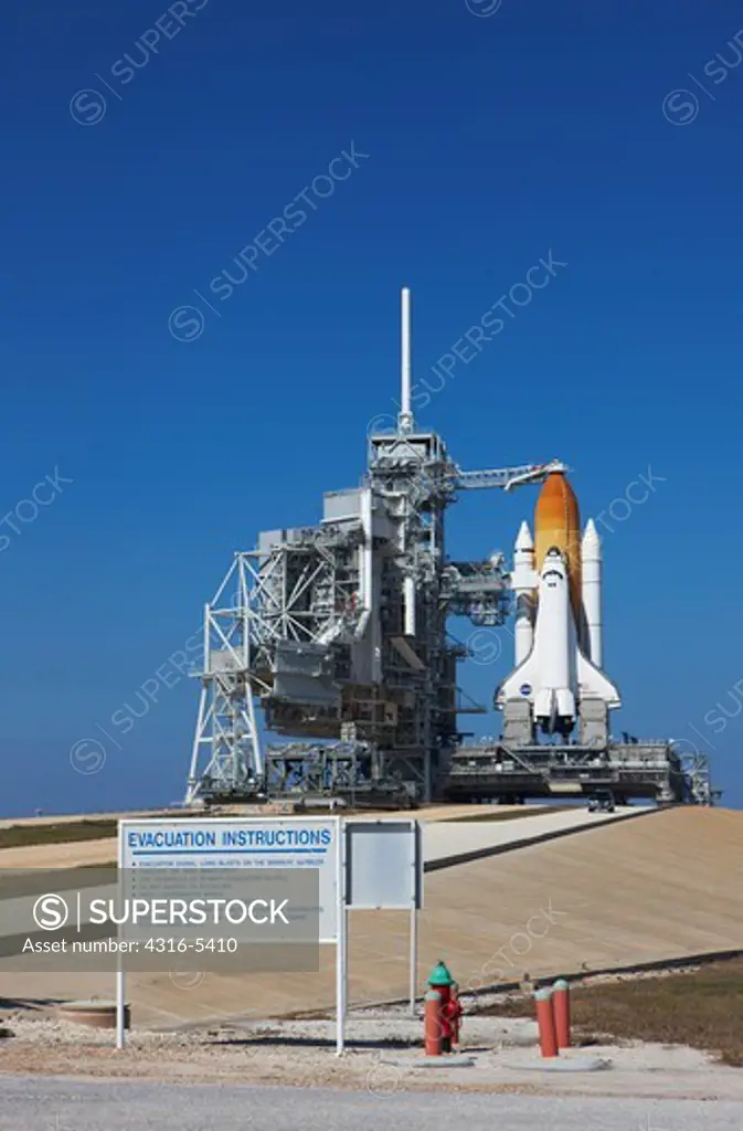 Space Shuttle Endeavour poised to launch on Space Transportation System 130 with the Rotating Service Structure rolled back and sign with evacuation instructions in foreground sitting on Pad 39A at Launch Complex 39, NASA Kennedy Space Center, Merritt Island, Florida, USA