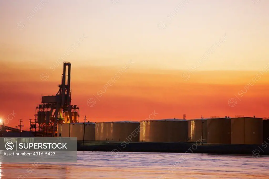 Large oil tanks and a container loader in distance, Mobile River, Mobile, Alabama, USA
