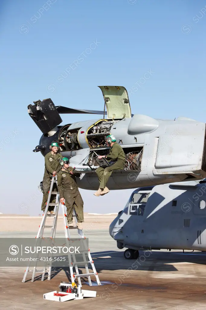 United States Marine Corps aircraft maintenance specialists working on an engine housed inside an engine nacelle of an MV-22 Osprey, Camp Bastion, Helmand Province, Afghanistan