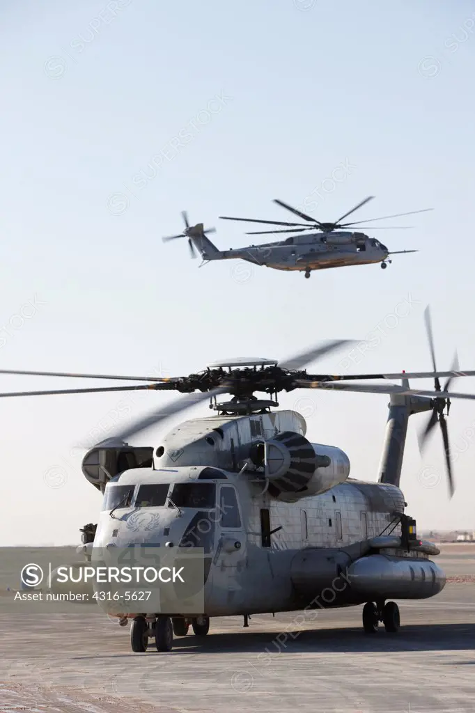 United States Marine Corps CH-53D Sea Stallion (foreground) taxis on the flightline at Camp Bastion, with a Marine Corps CH-53E Super Stallion lifting off, background, Helmand Province, Afghanistan