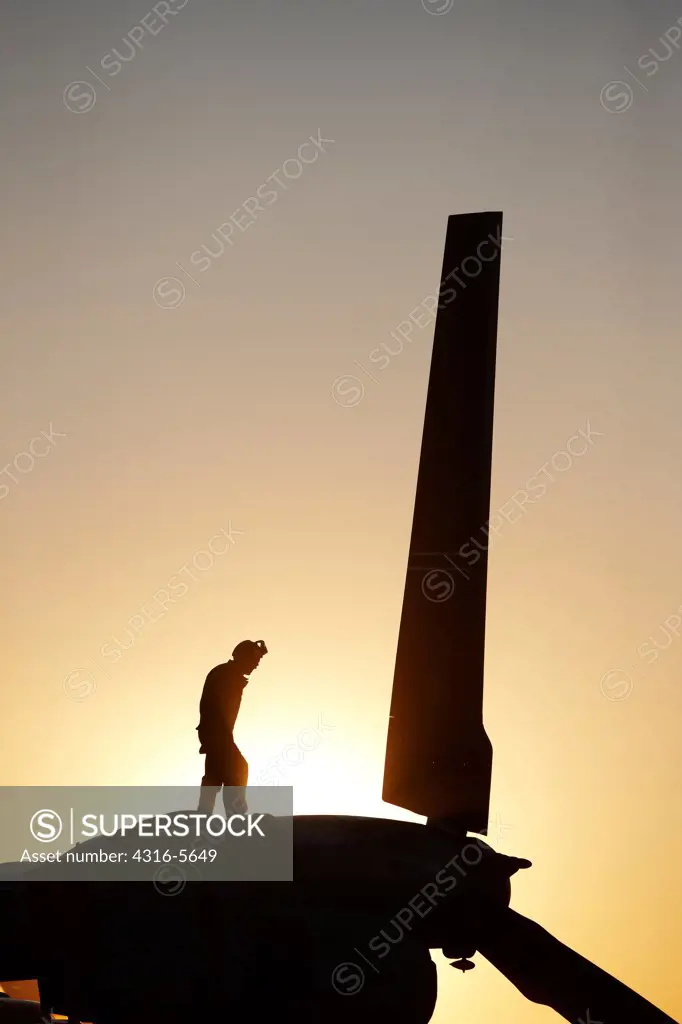 Silhouette of a United States Marine Corps aircraft maintenance specialist on an engine nacelle of an MV-22 Osprey, Camp Bastion, Helmand Province, Afghanistan