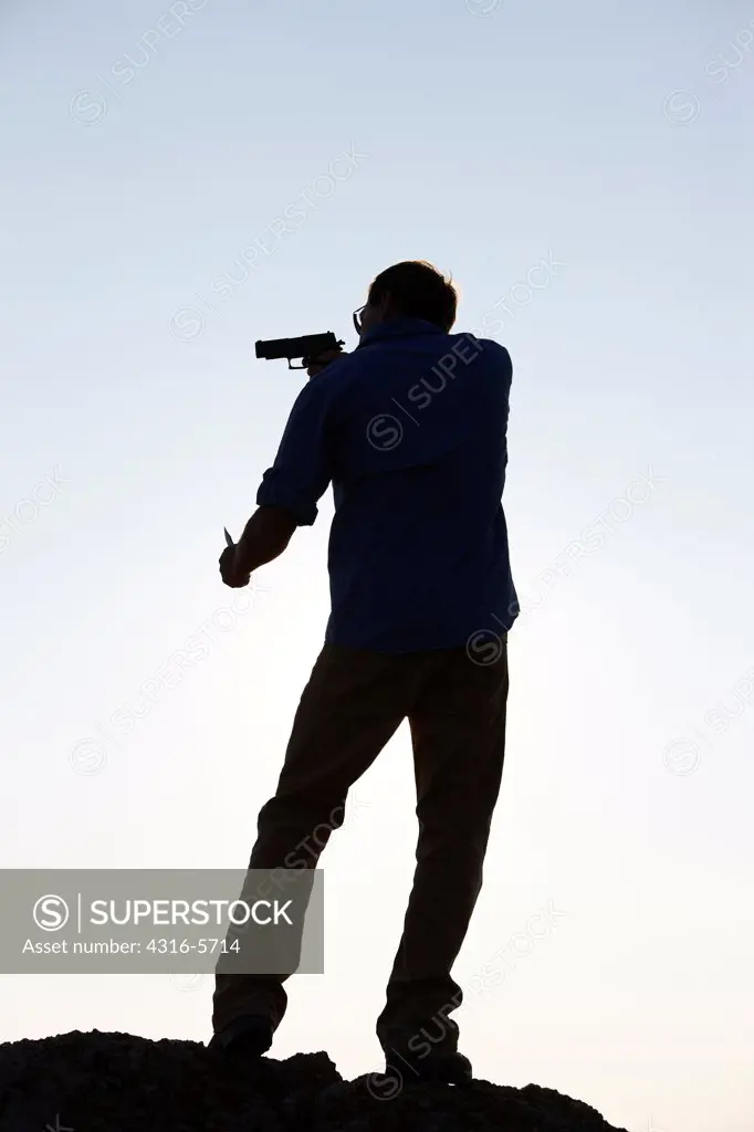 Silhouette of man holding handgun and knife