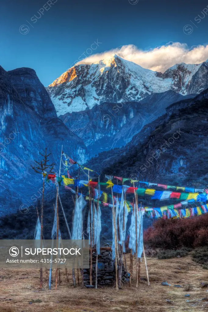 Nepal, Makalu-Barun National Park, Riphuk Kharka, Tibetan Prayer flags with peak of Hongku Chull in distance