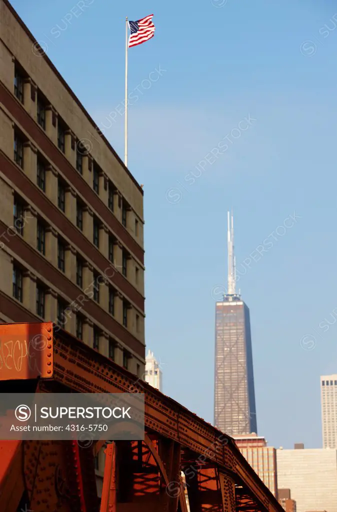 USA, Illinois, Chicago, John Hancock tower with American flag on office building in foreground